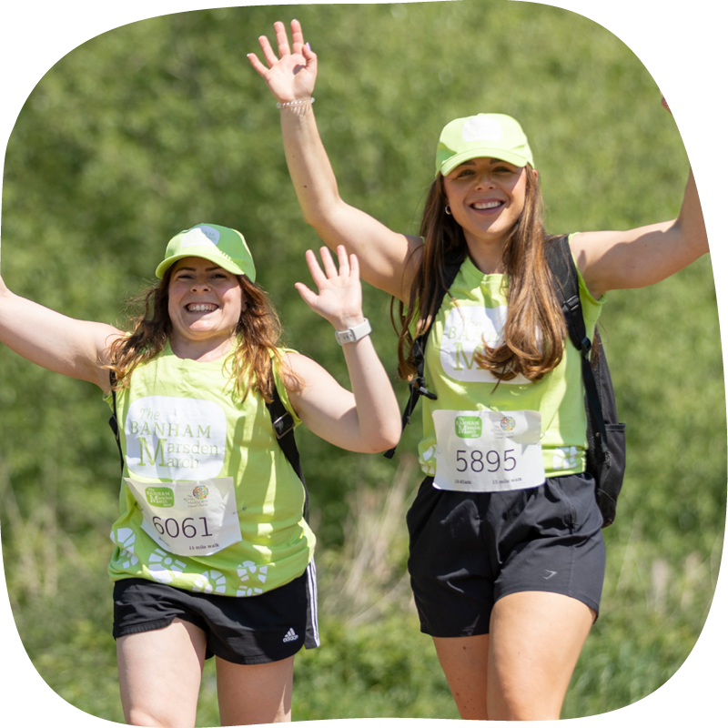 Two Banham Marsden Marchers, they're walking in a park, smiling with their hands up