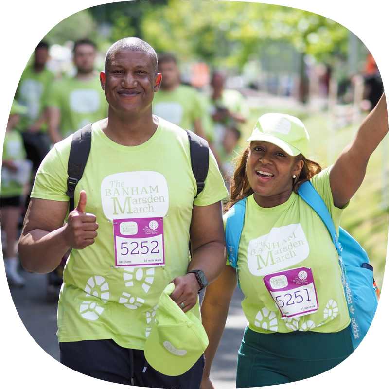 Two people taking part in the Banham Marsden March. One is giving a thumbs up, the other is smiling with their arm up in the air