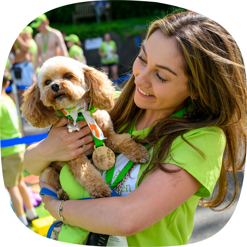 A Banham Marsden Marcher smiling and holding her small toy poodle, which has a medal around its neck. A Banham Marsden Marcher smiling and holding her small toy poodle, which has a medal around its neck.