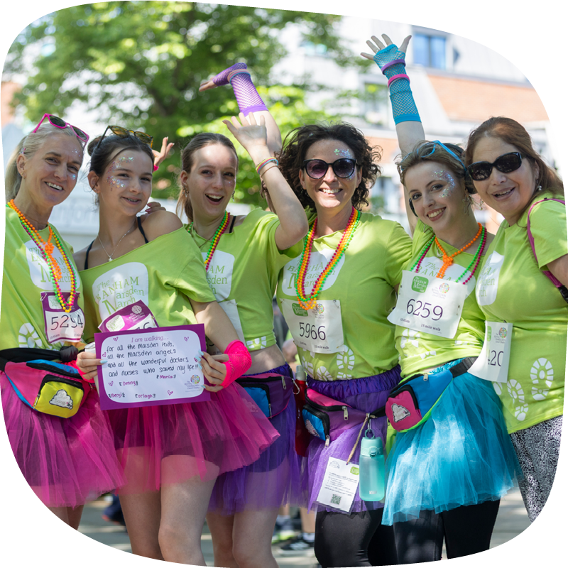 A group of people taking part in the Banham Marsden March. They're posing in colourful tutus and long beaded necklaces.
