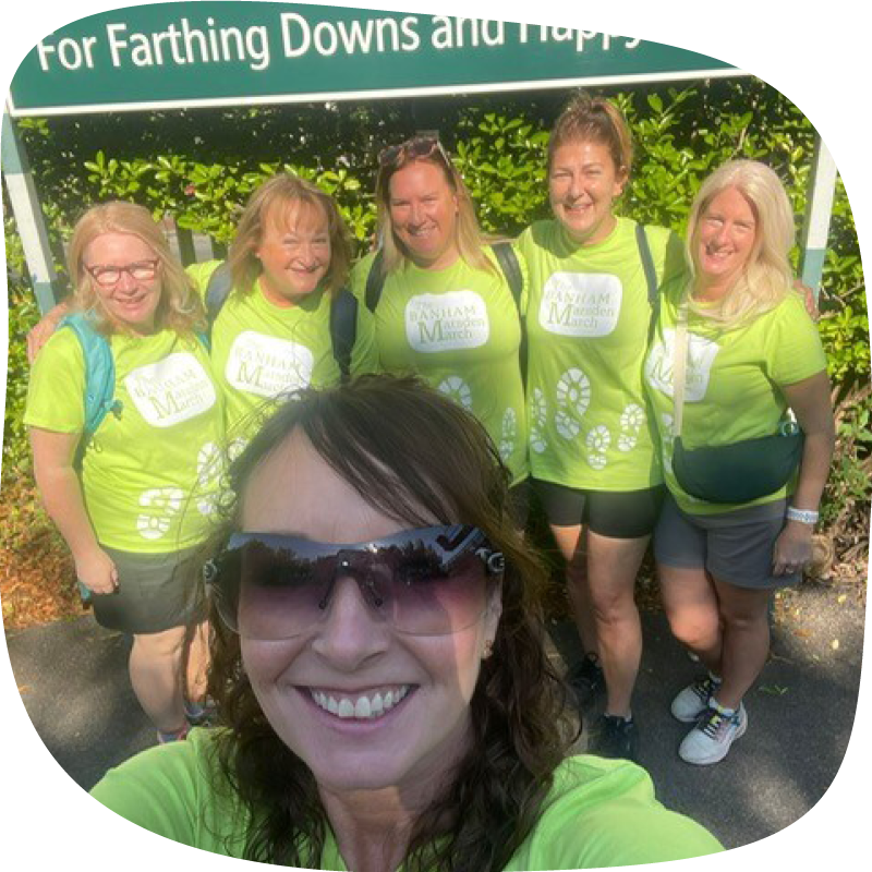 A group of Banham Marsden Marchers - one person is up the front, taking a selfie with five friends behind, standing together under a road sign.
